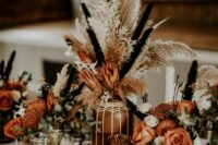 28 a western wedding centerpiece of patterned vases, rust and orange blooms, dried grasses and candles is amazing for a boho wedding