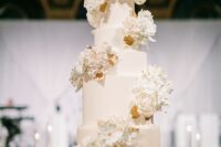 28 a white wedding cake with white sugar blooms and gold leaf swirls around it is a very chic and beautiful idea for a formal wedding