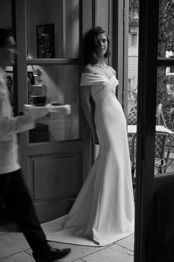 an elegant modern off the shoulder wedding dress with a draped bodice and a plain skirt with a train is pure chic