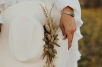 32 a creamy bridal hat with dried grasses and greenery plus a silver bracelet with an emerald for a western or boho bridal look