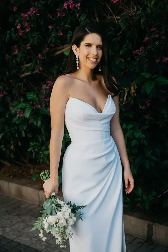 a beautiful and sexy strapless wedding dress with a draped bodice and skirt with a thigh high slirt plus nude heels and pearl earrings