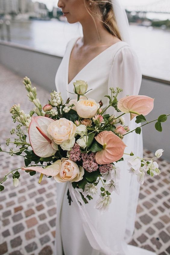 a modern pastel wedding bouquet with peony roses, blush anthurium and blooming branches is nice for a spring or summer wedding