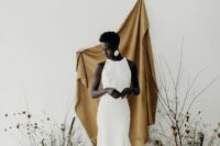 a sophisticated minimalist wedding backdrop of a mustard drape, dried blooms and branch arrangements is a gorgeous idea