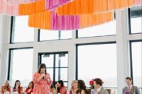 35 a modern wedding reception space with neutral tables but bright blooms and colorful streamers over the tables