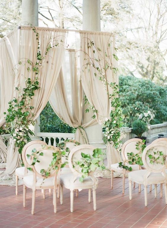 a sophisticated neutral wedding harbor done with tan drapes, greenery and white blooms is a very stylish idea for outdoors