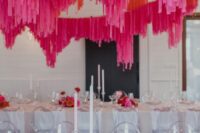 37 a neutral wedding reception space with white tables and pink and red blooms on the tables, hot pink and red streamers over the tables