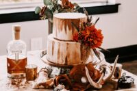 39 a boho western wedding cake in white and rust, with a bold bloom and dried flowers and greenery is a lovely and bold cakery piece