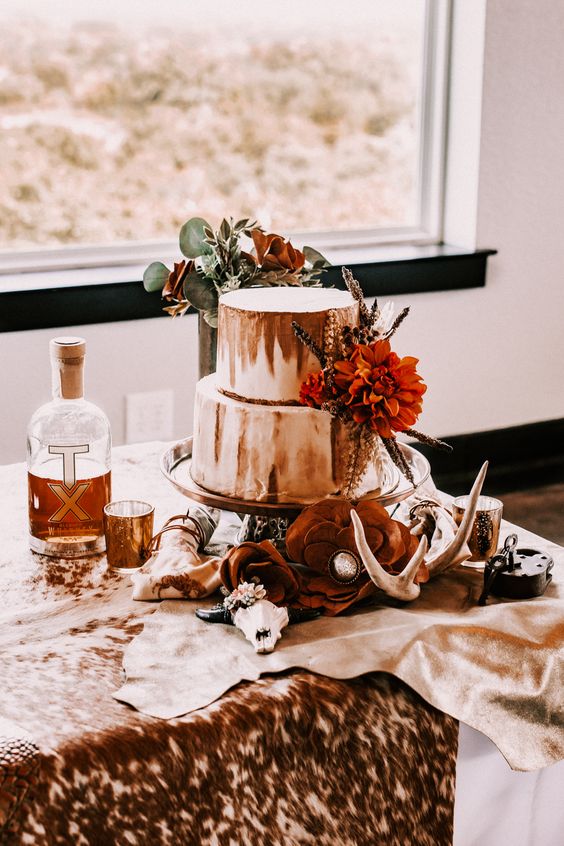 a boho western wedding cake in white and rust, with a bold bloom and dried flowers and greenery is a lovely and bold cakery piece