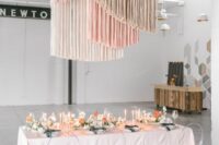 39 a romantic wedding reception space with a blush table and some neutral and bright blooms, blush, grey and creamy fringe over the table