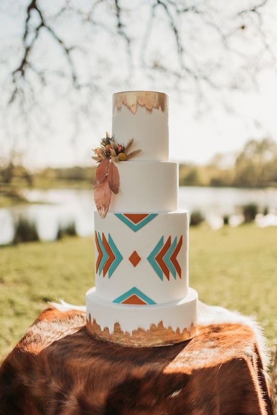 a boho western wedding cake with colorful geo detailing, dried grasses and gilded touches is a lovely idea for a western wedding