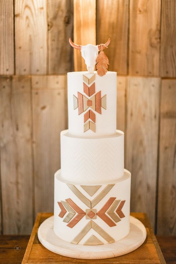 a classy western wedding cake with geometric sugar patterns and an edible skull on top is a cool and bold solution to highlight your wedding theme