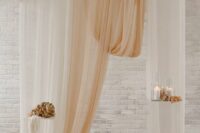 42 a modern wedding backdrop with neutral and peachy drapes, pillar candles, dried and fresh blooms is a beautiful and chic wedding decor idea