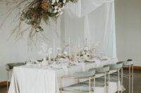 43 a beautiful wedding reception space with white drapes, white and coffee-colored blooms and branches, white flowers and candles