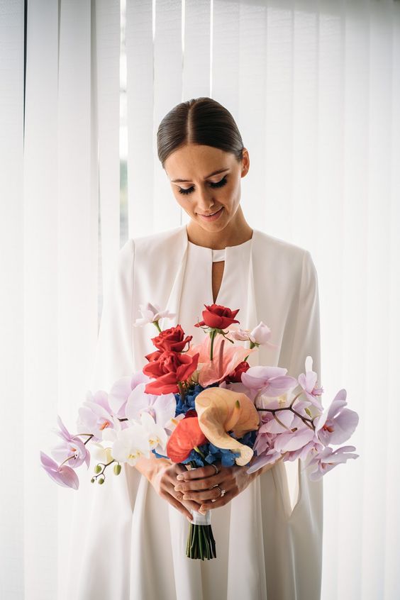 a sophisticated modern colorful wedding bouquet with pale pink orchids, red roses, white orchids and pink tropical blooms