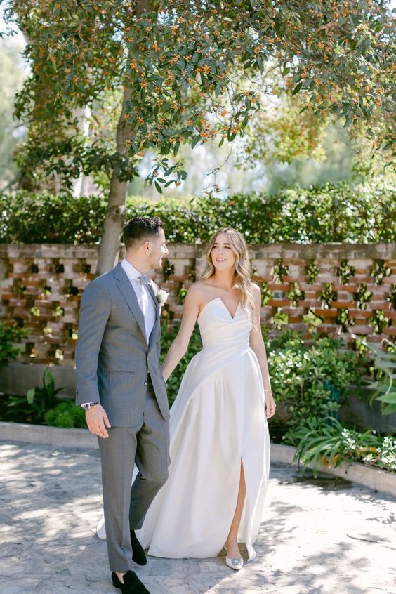 a strapless and sculptural wedding ballgown with a draped bodice and a pleated skirt with a front slirt, elegant buckle shoes