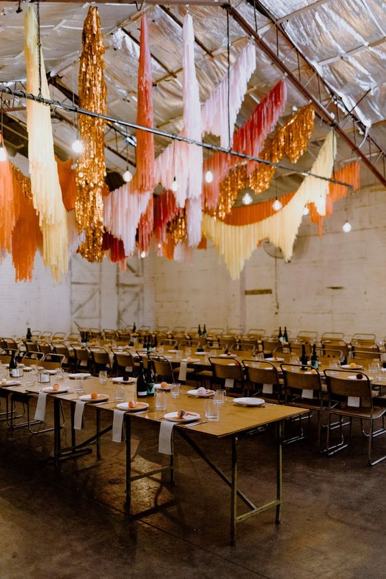 an industrial wedding reception with super bright streamers over the space as the main decor piece