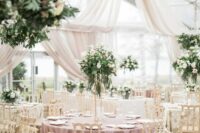 45 a dreamy and romantic wedding reception space with neutral drapes, mauve tablecloths, greenery and white blooms and elegant chairs