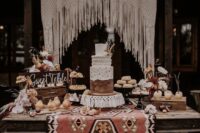 45 a western wedding dessert table with a woven rug, a western-style cake, cookies, pears and other sweets plus a macrame backdrop