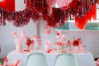 a bright pink and red wedding dessert station with pink, red and red tinsel streamers over the table is pure fun