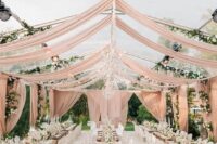 47 a neutral and elegant wedding reception space with blush drapes, stained tables, white chairs and neutral blooms