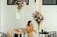 48 a pretty wedding lounge with a peachy sofa and black chairs and tables, a neutral and peachy draped and some neutral and pastel blooms
