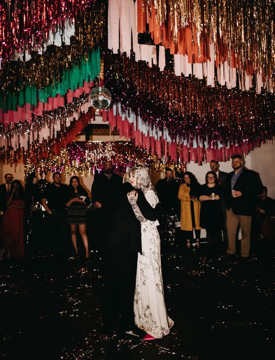 a wedding dance floor decorated with gold, burgundy, emerald and red streamers and a disco ball is a fantastic idea