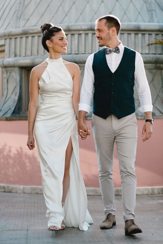 an ultra-modern plain halter neckline wedding dress with a draped bodice and skirt plus a thigh high slit and white shoes