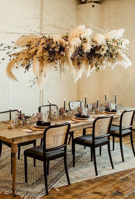 a beautiful and bold overhead wedding installation with pampas grass, dark foliage and branches is a lovely idea for a boho wedding