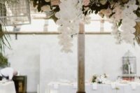 a beautiful overhead floral installation with blush and white roses and orchids, baby’s breath and cages is a creative idea for any modern refined wedding
