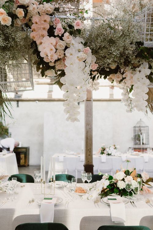 a beautiful overhead floral installation with blush and white roses and orchids, baby's breath and cages is a creative idea for any modern refined wedding