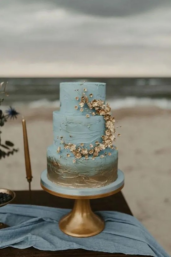 a blue and gold textural wedding cake with gold touches and gold blooms plus beads for decor is a dreamy idea for a beach or coastal wedding