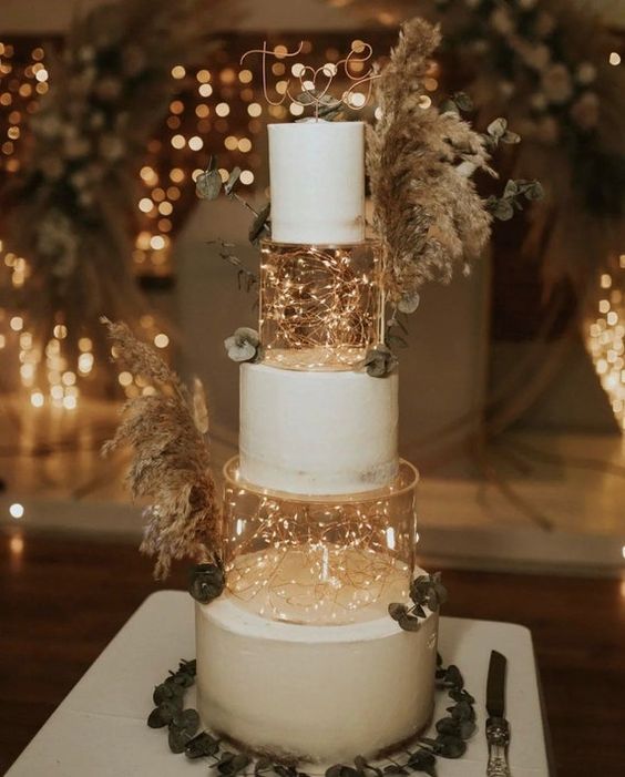 a boho white wedding cake with two clear tiers filled with LED lights, pampas grass and eucalyptus is amazing for a boho wedding