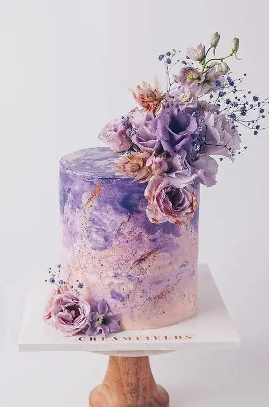 a breathtaking blush to purple watercolor wedding cake decorated with copper glitter, fresh lilac and pink blooms is a bold statement