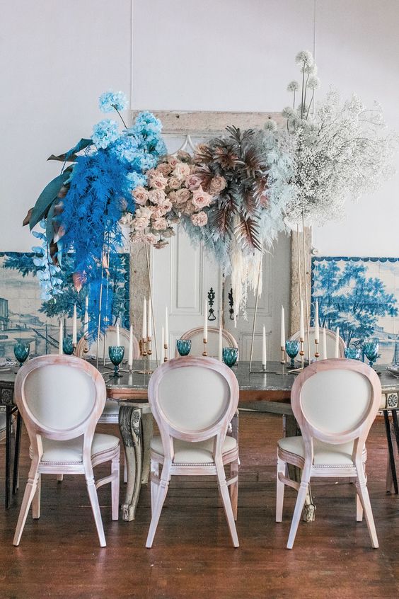 a bright and catchy floral wedding installation with blush roses, blue hydrangeas, bold blue and dark leaves, baby's breath is a fantastic accent