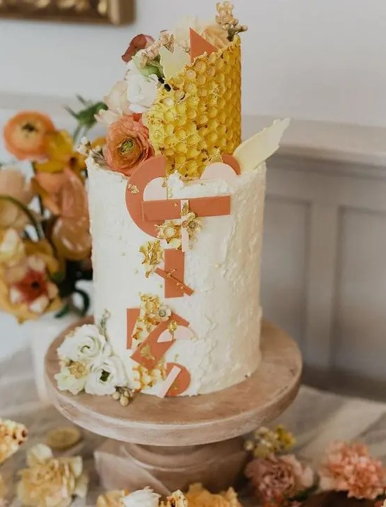 a bright and fun 70s wedding cake with a textural and patterned tier in yellow, with fresh blooms and creative edible monograms