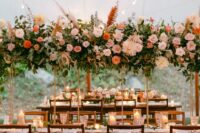 a catchy and lovely floral installation with blush, coral and pink blooms, leaves and pampas grass is a cool idea for a summer wedding