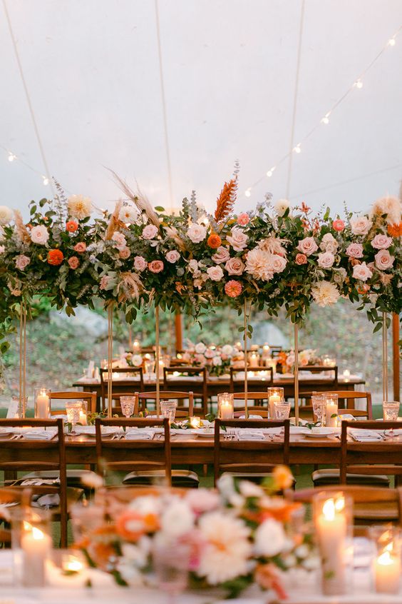 a catchy and lovely floral installation with blush, coral and pink blooms, leaves and pampas grass is a cool idea for a summer wedding