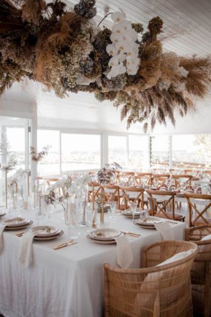 a catchy dried flower and grass wedding installation with white orchids is a chic and bold boho wedding idea
