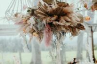 a cool colorful dried wedding installation with usual, peachy and pink pampas grass, white and peachy blooms and dried fronds