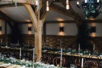 a creative cascading greenery overhead wedding decoration with bulbs hanging down and a matching greenery runner