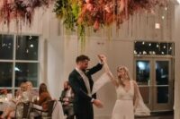 a dance floor accented with a fantastic colorful overhead installation of pampas grass and some hanging parts is gorgeous