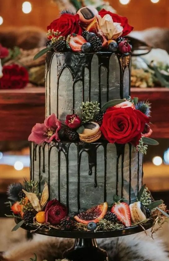 a decadent fall wedding cake in grey, with chocolate drizzle, bright blooms, citrus, berries and greenery