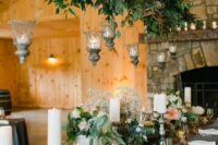 a dried branches and greenery wedding decoration with candle lanterns for a secret garden wedding