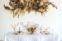 a dried grass and frond overhead wedding installation with branches and leaves is a catchy idea for a neutral boho wedding