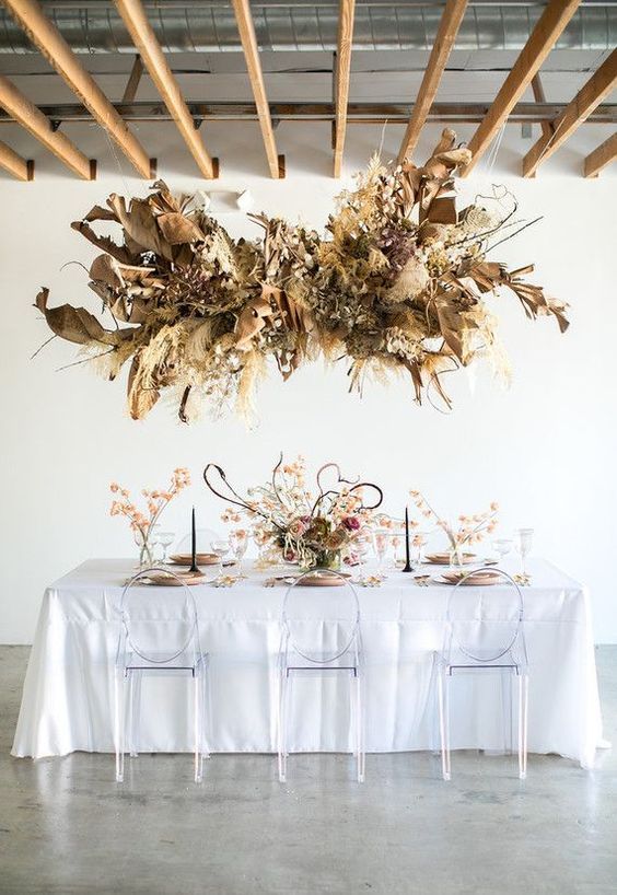 a dried grass and frond overhead wedding installation with branches and leaves is a catchy idea for a neutral boho wedding