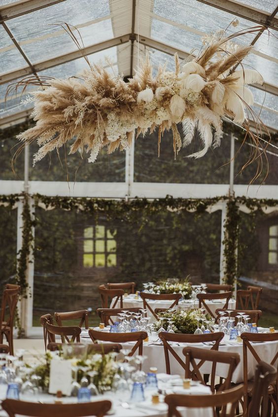a dried grass wedding installation with pampas grass, leaves, branches and some dried white blooms is amazing