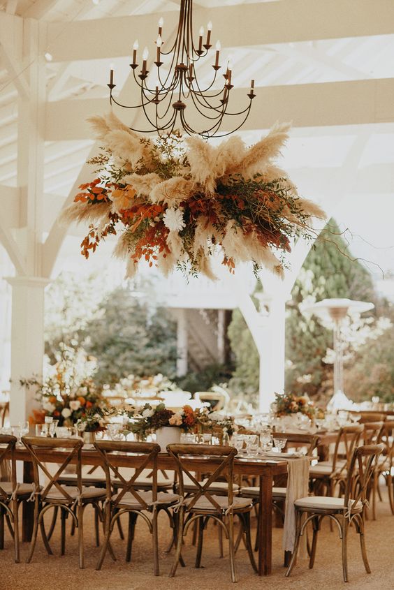 a dried leaf and grass wedding installation with pampas grass, greenery, branches, bold fall foliage is amazing for a fall boho wedding
