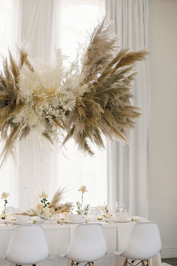 a dried leaf wedding installation of pampas grass, leaves and some small dried blooms is a catchy and cool idea for a neutral boho wedding
