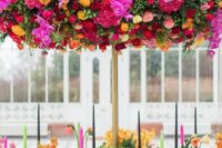 a fantastic colorful overhead wedding installation with hot pink, burgundy, yellow and pink blooms and greenery is wow