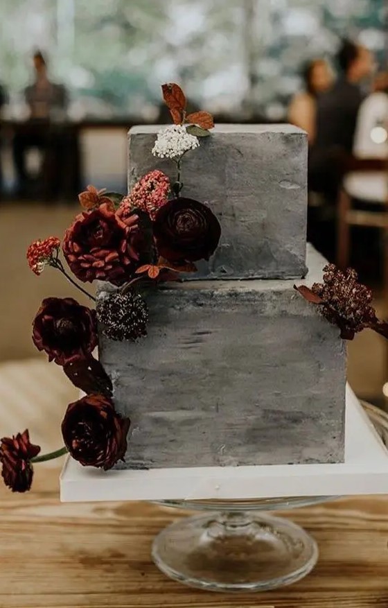 a grey concrete wedding cake with bold dried and fresh blooms and leaves is a stylish wedding dessert idea